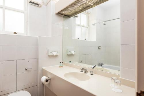 a white bathroom with a sink and a mirror at Coulsdon Manor Hotel and Golf Club in Croydon