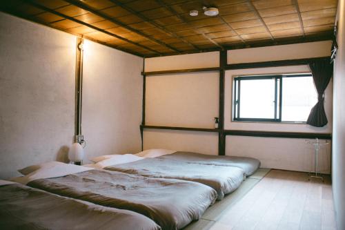 two beds in a room with a window at サカナギゲストハウス in Nagano