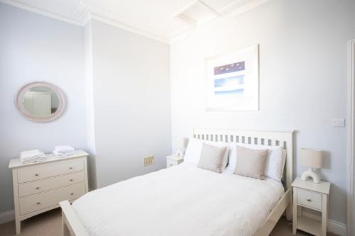 a white bedroom with a bed and a mirror at Seaview in Worthing