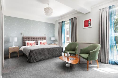 a bedroom with a bed and a chair and a table at Coulsdon Manor Hotel and Golf Club in Croydon