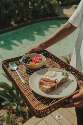 a table with a plate of food and a bowl of fruit at Pousada Topázio by Amana in Fernando de Noronha
