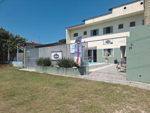 a building with a fence next to a yard at Pousada Recanto Vo da Maria com Piscina a 440mt da praia in Pontal do Paraná