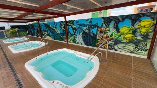 a jacuzzi tub in a room with a mural at Apto Aquarius - Piscinas Aquecidas, Hidro e Lazer Total - até 5 Pessoas in Caldas Novas