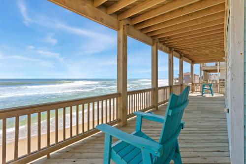 a blue rocking chair sitting on a porch overlooking the beach at 8046 - Sun Runner in Rodanthe