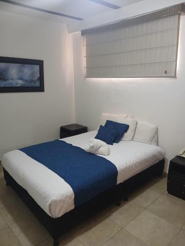 a bedroom with a large bed with blue and white sheets at Hotel estación Kristal - Corferias in Bogotá