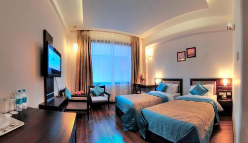 um quarto de hotel com duas camas e uma televisão de ecrã plano em The Retreat em Agra