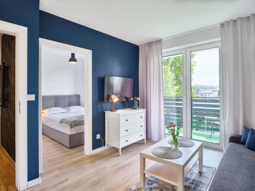 a bedroom with blue walls and a bed and a table at Slow Łeba Relaksowa - Apartamenty z aneksami kuchennymi in Łeba