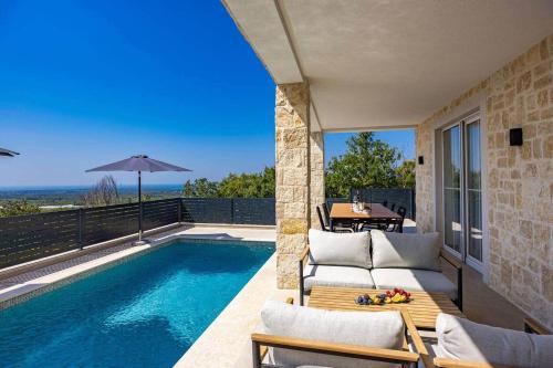a patio with a pool and a table and chairs at Villa Bella Vista with Pool and Seaview in Labinci