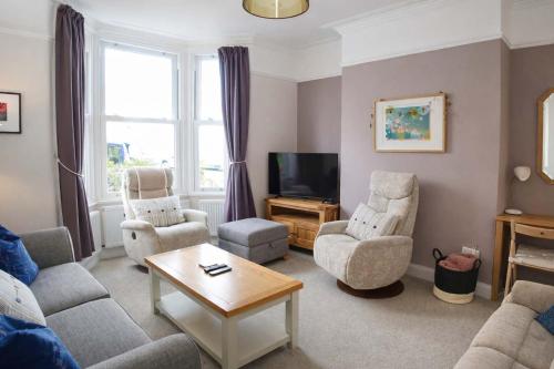 a living room with a couch and chairs and a tv at Totterdown's Fabulous House & Floral Garden in Bristol