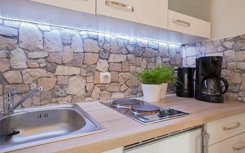 a kitchen with a sink and a stone wall at Gästehaus Babel in Pfronten