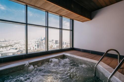 a jacuzzi tub in a room with windows at Radisson Collection Residences, Riyadh in Riyadh