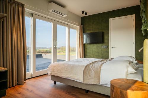 a bedroom with a bed and a large window at Hotel Biedeboom in 's-Heer-Hendrikskinderen