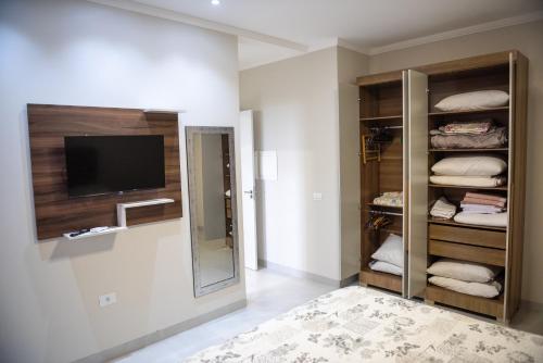 a room with a tv and a closet with towels at Condomínio Pagani in Foz do Iguaçu