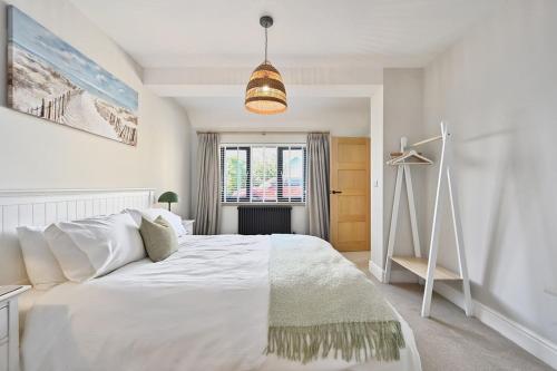 a bedroom with a large white bed and a window at Xanadune Beach House by Bloom Stays in Greatstone