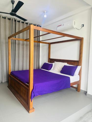 a bedroom with a canopy bed with purple sheets at Naadee villa in Ekala