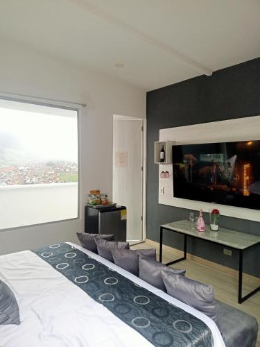 a bedroom with a large bed and a tv at Mirador samsara Jacuzzi al aire libre 60 m2 in La Calera
