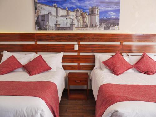 a bedroom with two beds with red pillows at Casona Urinsaya Qolca in Chivay