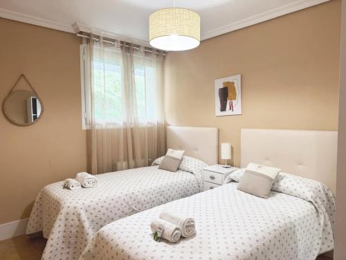 zwei Einzelbetten in einem Zimmer mit weißer Bettwäsche in der Unterkunft Comillas playa in Comillas