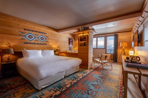 a hotel room with a large bed and a desk at Chalet Hotel Kaya in Les Menuires