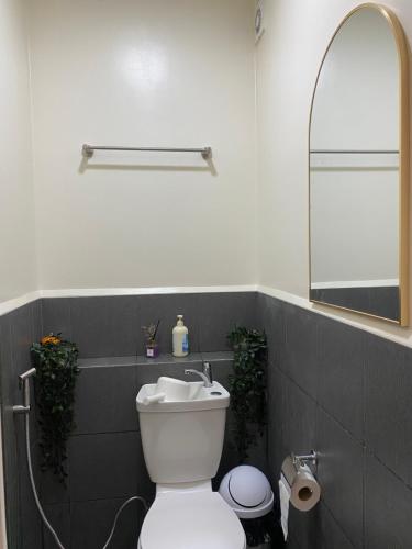 a bathroom with a white toilet and a mirror at Casa Ona in Manila