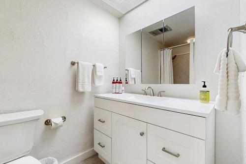 a white bathroom with a sink and a mirror at Kalanikai #112 in Kailua-Kona