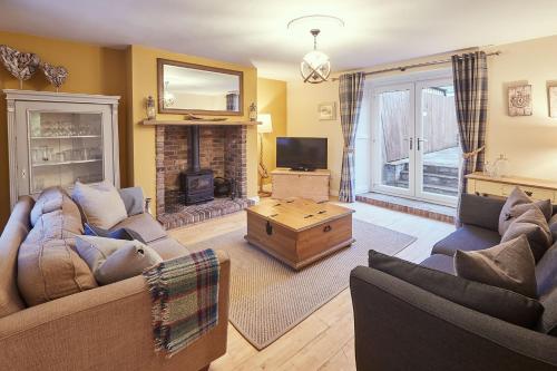 a living room with two couches and a fireplace at Church Cottage by Coast & Country Stays in Beadnell