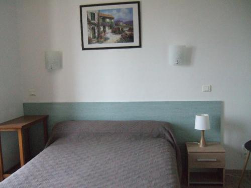 a bedroom with a bed and a picture on the wall at Auberge le Cévenol in La Cavalerie