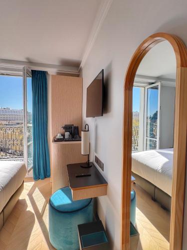 a hotel room with a desk and a bed and a window at Eiffel Yard Hotel in Paris