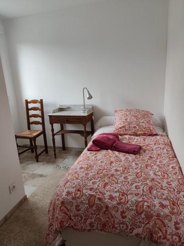 a bedroom with a bed with a table and a chair at Le Rocher au Thym in Limoux