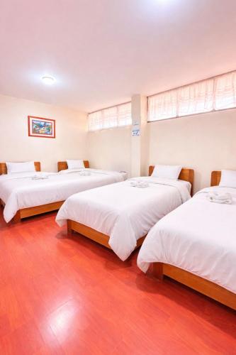 a room with three beds with white sheets at HOTEL IBYZA Ipiales in Ipiales
