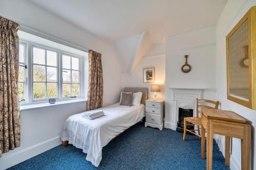 a bedroom with a bed and a desk and a window at Amys Cottage in Sherborne