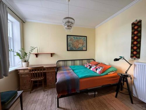 a bedroom with a bed and a desk and a lamp at Solkot Cottage Homestay in Reykjavík