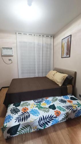 a bedroom with a bed with a flower patterned blanket at Manila Bay City Lights in Manila