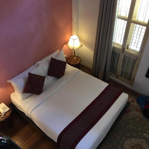 a bedroom with a white bed with a lamp and a window at Spices Hotel in George Town