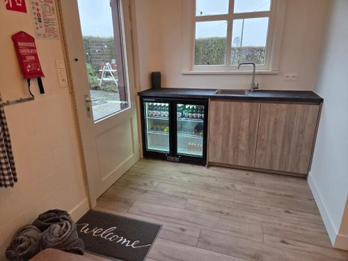 an empty kitchen with an open refrigerator next to a window at De Horizon in de Westhoek in Poperinge