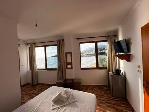 a bedroom with a bed and two windows and a television at Beleris Rooms in Himare