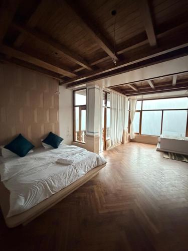 a bedroom with a large bed in a room with windows at The Swayambhu Hamta in Manāli