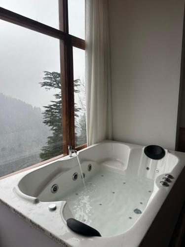 a white bath tub in front of a window at The Swayambhu Hamta in Manāli