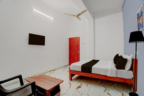 a bedroom with a bed and a table and a chair at Super Hotel Redmoon Residency Elite in Chennai