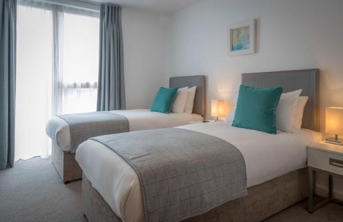 two beds in a hotel room next to a window at Talbot Suites at Stonebridge in Wexford