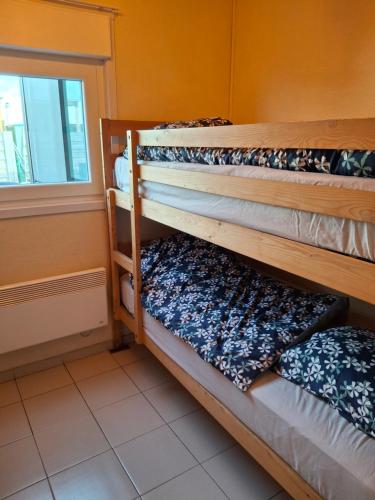 two bunk beds in a room with a window at Maison de vacances Etoile de mer 2 in Koksijde