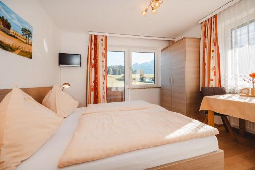 a bedroom with a bed and a table and a window at Unterwötzlhof in Abtenau
