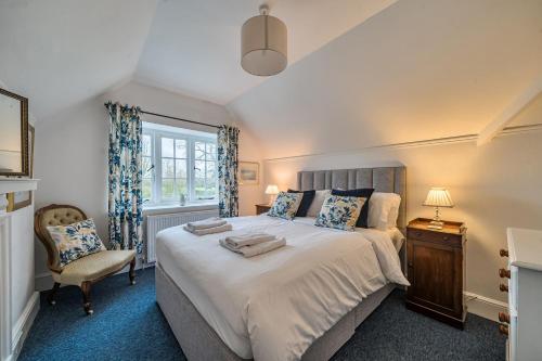 a bedroom with a bed and a chair and a window at South Cottage in Sherborne