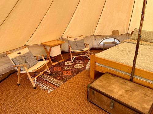 a tent with two chairs and a bed and a table at Camping équipé : Vallon de Laborie in Astaillac