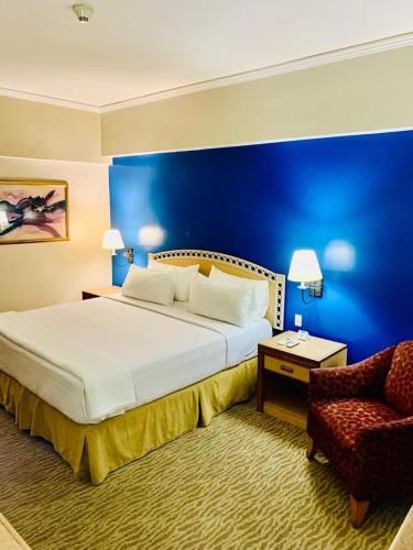 a bedroom with a large bed and a chair at Intercity Tower Hotels in San Pedro Sula