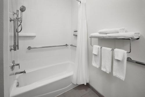a white bathroom with a bath tub and towels at Garner Hotel Lincoln North by IHG in Lincoln