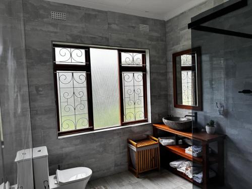 a bathroom with two windows and a sink and a toilet at Berna Coastal Retreat in Port Shepstone
