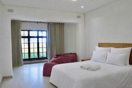 a bedroom with a large white bed and a chair at Berna Coastal Retreat in Port Shepstone