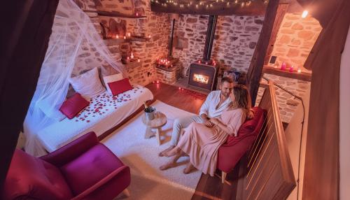 a man and woman sitting in a room with a fireplace at Le Puits Enchanté in Espalion