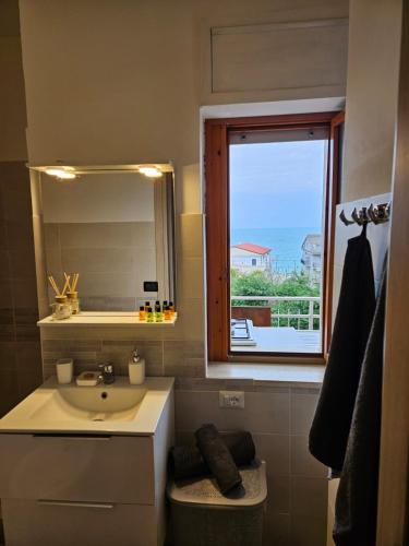a bathroom with a sink and a mirror and a window at Appartamento Rosa Calabria in Roseto Capo Spulico
